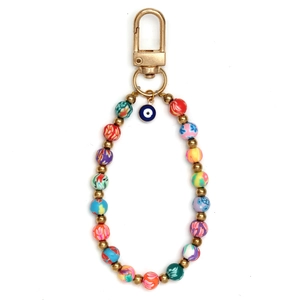 Detalle de cuentas florales de colores y amuleto ojo azul en llavero dorado con D
