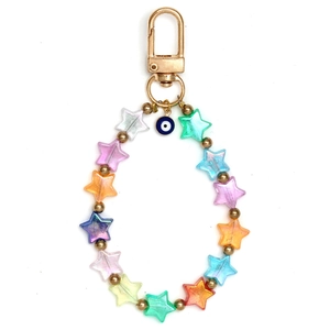 Detalle de cuentas de estrella coloridas y dije de ojo azul en un llavero dorado elegante