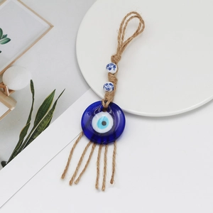 Detail of evil eye glass charm with hemp rope tassel and blue patterned ceramic beads