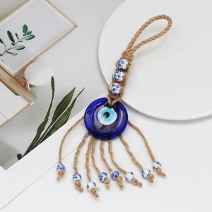 Macro detail of Evil Eye glass pendant with ceramic beads and braided hemp rope tassel