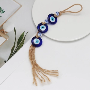 Close-up of Evil Eye hanging ornament with blue glass beads and natural jute tassels