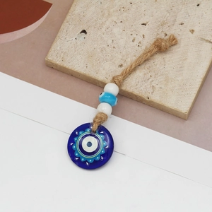 Detailed macro view of Turkish Evil Eye pendant with blue glass beads and jute rope texture