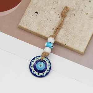 Detail view of evil eye keychain with hemp rope, blue flower pendant, and white beads