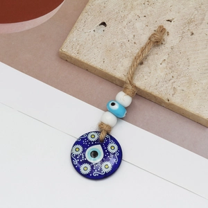 Detail of blue Evil Eye glass pendant with daisy pattern on natural hemp rope