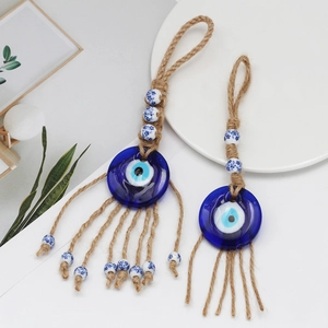 Close-up of glass Evil Eye wall hanging with woven hemp rope and painted ceramic beads