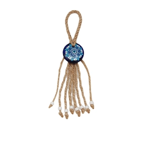 Detail of handmade evil eye charm with natural hemp rope weave and white bead tassels