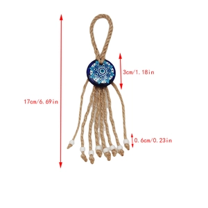 Detailed view of evil eye wall hanging with white beads, jute rope and tassel fringe
