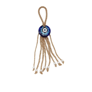 Detail of evil eye nazar pendant with blue glass eye bead and braided hemp rope tassels