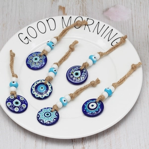 Detail view of six Nazar evil eye glass pendants with jute ropes on a white plate