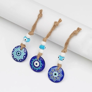 Close-up of three Evil Eye pendants with mandala floral patterns and braided rope cord
