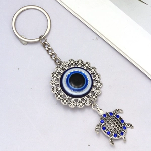 Detail showing an evil eye charm with a silver turtle pendant inlaid with blue crystals