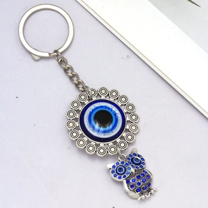 Detailed close-up of a silver owl keychain with sparkling blue rhinestones and a Nazar evil eye