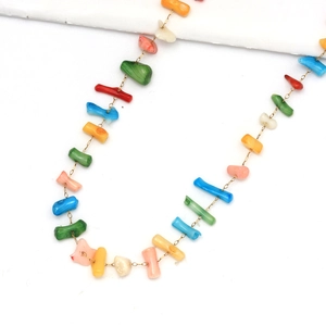 Détail de perles de pierre multicolores sur une fine chaîne dorée aux tons vibrants