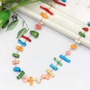 Détail de perles de pierre naturelle colorées sur une fine chaîne de collier dorée