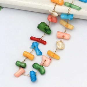 Gros plan d'un collier bohème avec des perles multicolores et des maillons de chaîne dorés