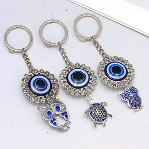 Detailed close-up of elephant owl and turtle evil eye keychains with blue rhinestones