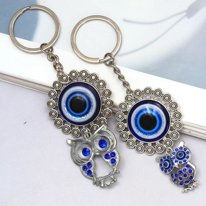 Close-up of owl evil eye keychains with sparkling blue crystals and silver metal chains