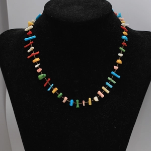 Gros plan d'un collier bohème en pierres naturelles colorées sur un présentoir en velours