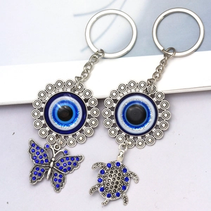 Blue evil eye keychains with butterfly and turtle charms on a minimalist background
