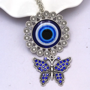 Detail of silver Evil Eye keychain featuring a blue crystal butterfly and sun charm