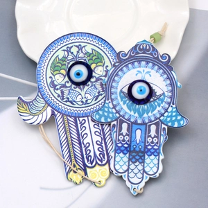 Detailed close-up of Hamsa Hand and round Evil Eye charms with intricate fish patterns