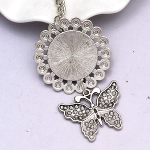 Macro detail of silver metal butterfly charm and retro textured circular pendant back