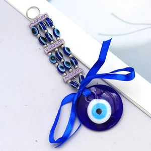 Macro detail of Turkish Evil Eye pendant with blue ribbon bow and beaded chain