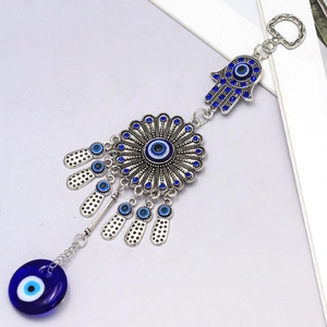 Close-up of silver Hamsa Hand and Evil Eye pendant with blue rhinestones and glass bead
