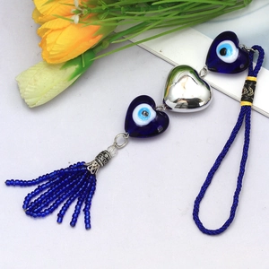 Detail of blue evil eye heart charms with beaded tassels on white floral background