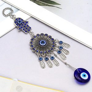 Detail of Hamsa Hand and Evil Eye keychain with blue rhinestones on a white book