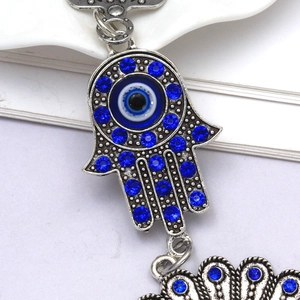 Detailed macro view of Hamsa Hand and Evil Eye pendant with blue rhinestones