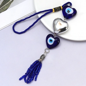 Detail of blue glass evil eye heart charms with woven cord and beaded fringe