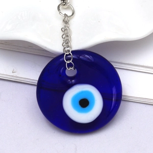 Close-up of glass evil eye pendant with blue concentric circles and silver metal keychain
