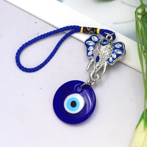 Detail of blue evil eye elephant keychain with metallic textures and woven cord