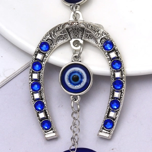 Détail d'un porte-clés fer à cheval en argent avec charm œil bleu et gravures