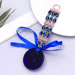 Detailed macro view of a blue Evil Eye charm with ribbon and intricate beads