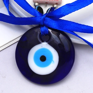Macro detail of Evil Eye glass pendant with royal blue silk ribbon and metallic beads