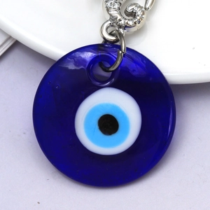 Detailed close-up of blue glass evil eye pendant with silver lobster clasp and metal ring