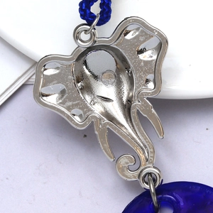 Macro view of silver elephant pendant back with detailed metal casting and blue cord