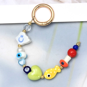 Detail of colorful beads including evil eye, smiley cloud and mushroom on a gold keychain
