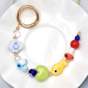 Colorful evil eye keychain with evil eye beads and mushroom charm on white ceramic plate