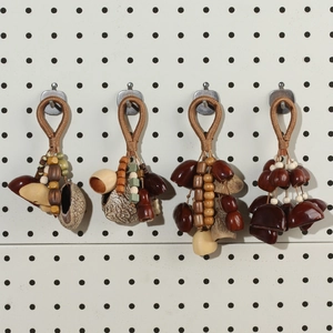 Close-up of four handmade natural seed shell pendants hanging on a white grid wall