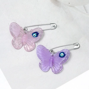 Detail view of pink and purple acrylic butterfly pins with evil eye charm accents