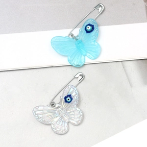 Detail of acrylic butterfly brooches with evil eye charms in blue and iridescent white