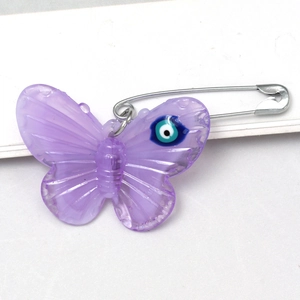 Macro shot of purple acrylic butterfly brooch with blue evil eye detail and silver pin