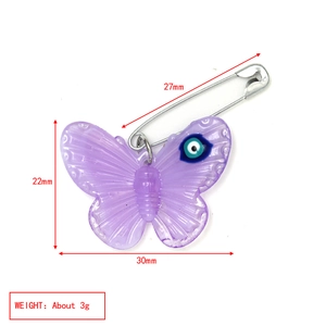 Acrylic purple butterfly brooch with blue evil eye detail on a silver safety pin