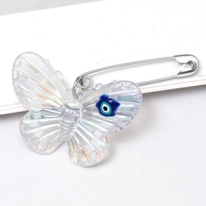 Macro detail of acrylic butterfly brooch pin with blue evil eye charm and iridescent finish