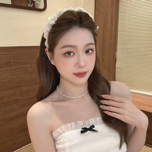 Gros plan sur un serre-tête en seersucker blanc et collier de perles pour femme