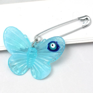 Close-up of light blue acrylic butterfly brooch with Evil Eye pattern and metal safety pin