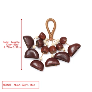 Detailed view of handmade natural nut shell shaker with woven handle and measurement data